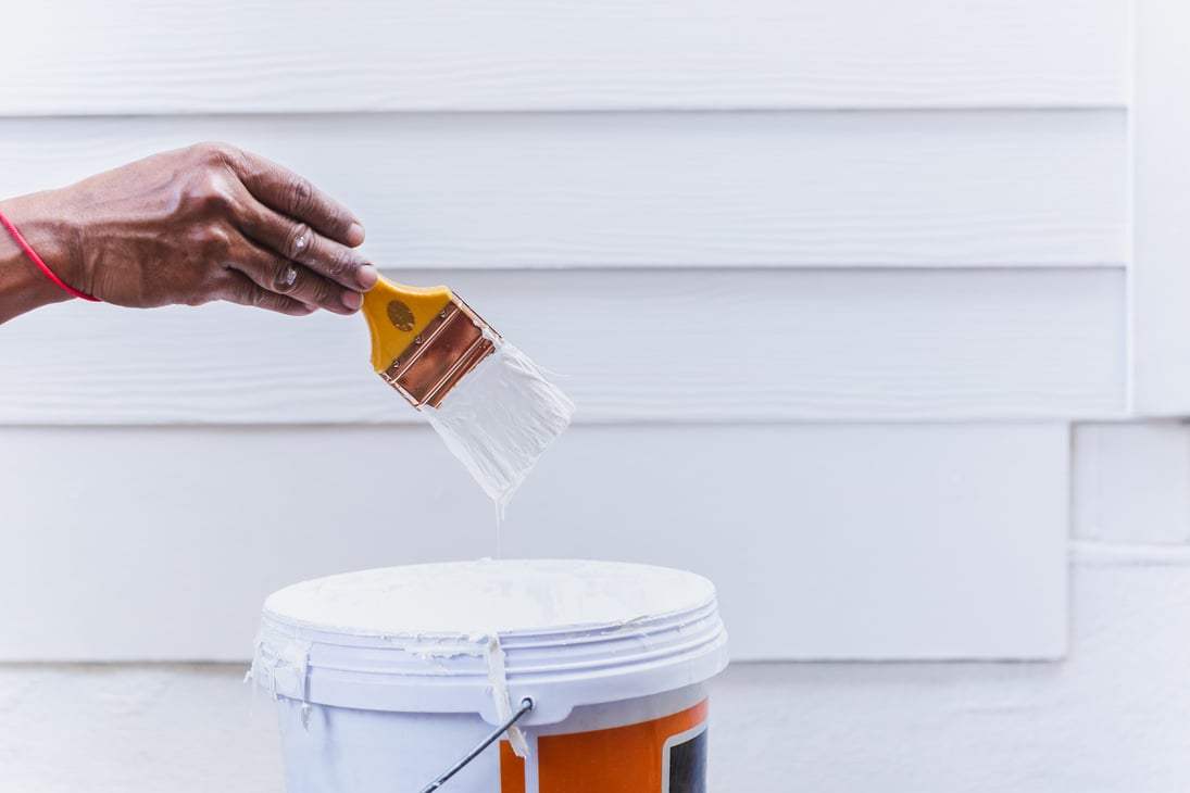 Painter hand holding paint brush with white paint.